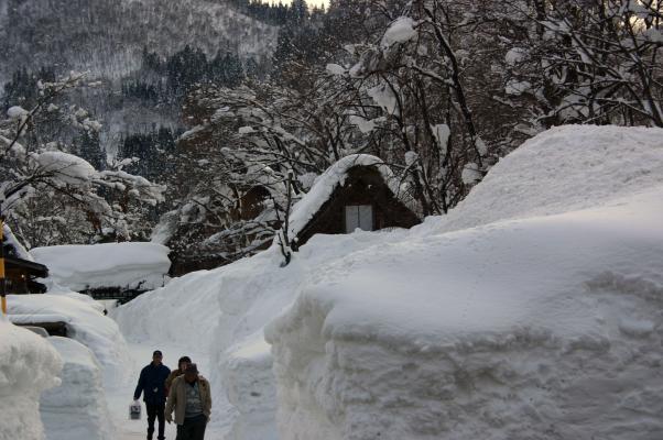 冬の飛騨白川郷、雪壁の道を歩く人びと
