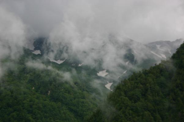 朝霧が流れる黒部渓谷と雪渓