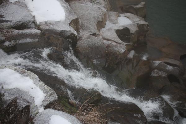 雪の岩場を流れ落ちる渓流