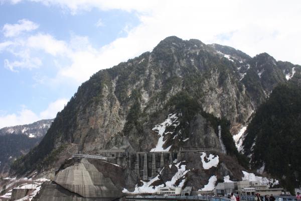 残雪の黒部ダムの岩崖とコンクリート壁