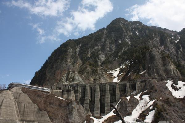 雪が残る黒部ダムの岩壁とコンクリート壁