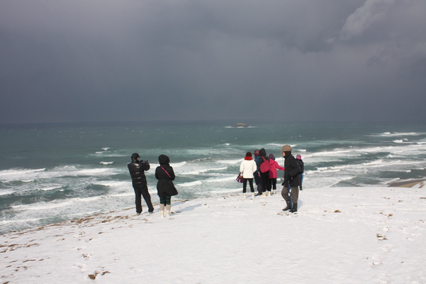 積雪の鳥取砂丘「馬の背」から日本海を見る人々