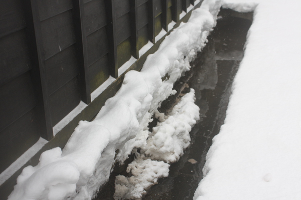 黒い板塀と積雪の用水路