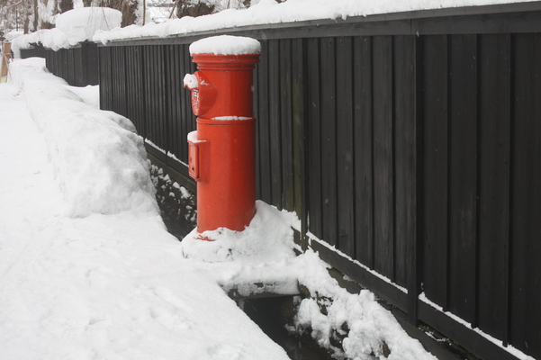 積雪の黒板塀と赤いポスト