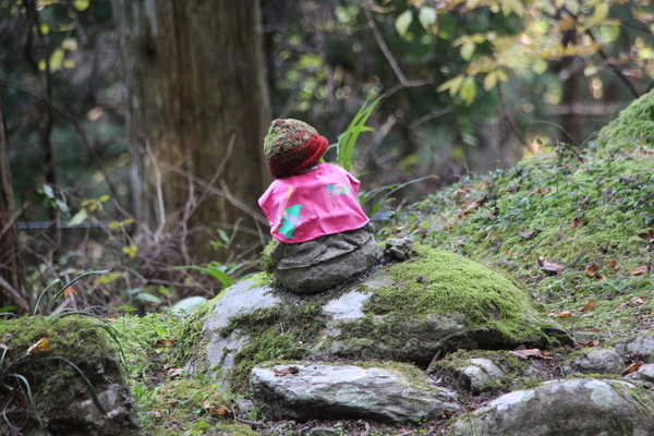 苔むした岩に座る赤い帽子の石仏さん
