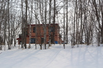 積雪と冬木立に囲まれた家
